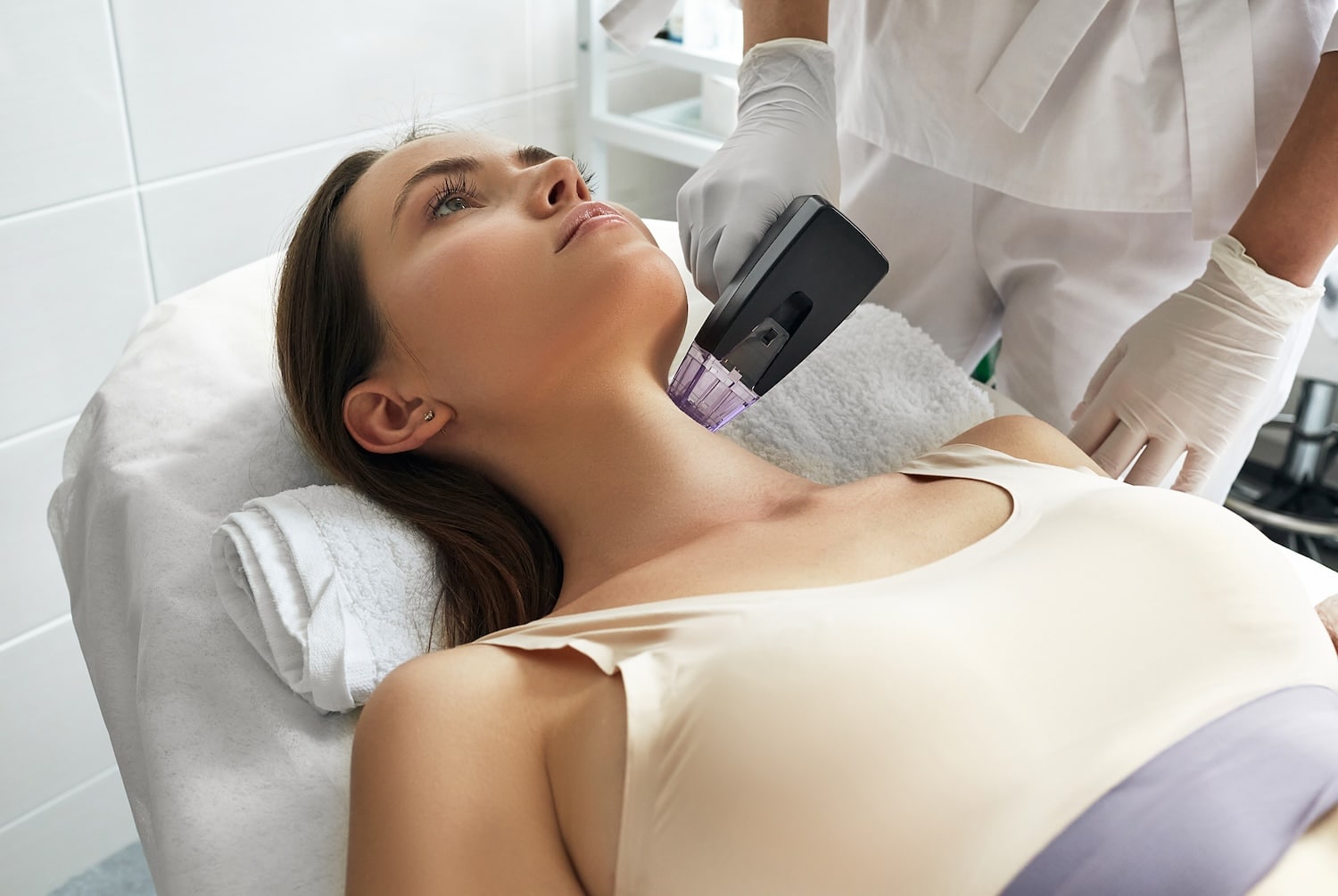 Beautiful woman enjoys while rf lifting procedure for her neck and body skin tightening with cosmetologist at beauty salon